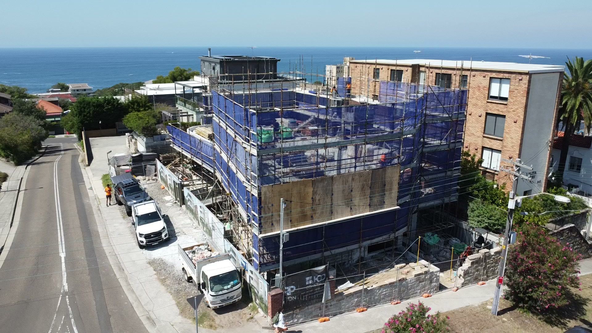 Aerial view of the Coogee project wrapped in scaffold, with the ocean behind