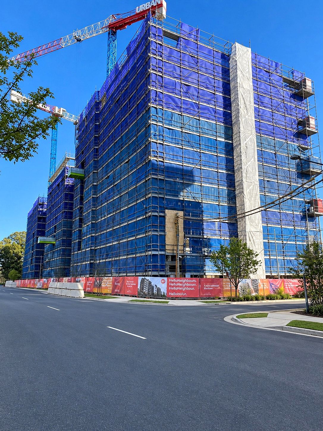 Lumina at Thornton, Penrith: a nine-storey apartment development wrapped in Ozscaf scaffold under two tower cranes