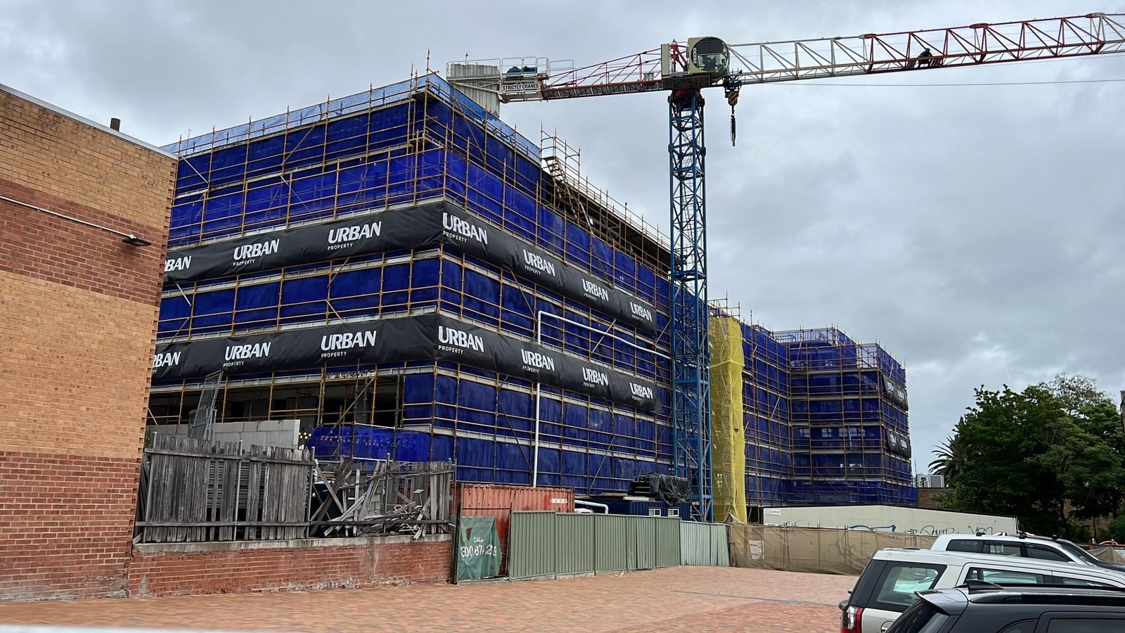 The Parq, Bexley, wrapped in Ozscaf scaffold with Urban Property hoarding, tower crane above